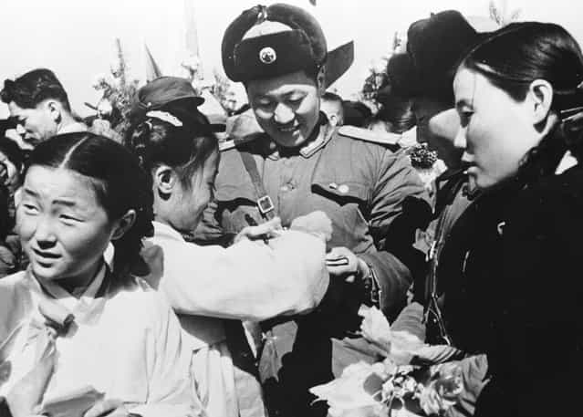 Korean girls present a member of the Chinese Peoples Volunteer Army with a bouquet of flowers prior to the mass withdrawal of Chinese troops from North Korea, 29th March 1958. (Photo by Keystone)