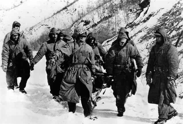 Marines carry a wounded comrade through snow to a cleared airstrip for evacuation during the Korean War, 1950. (Photo by Keystone)