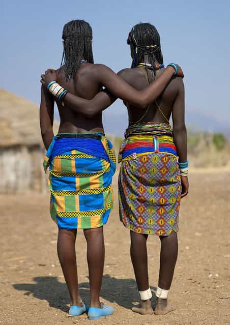 [Show us our butts! Mucawana tribe – Angola. In Soba village, the Muhacaona (Mucawana) tribe, perhaps the best place i have visited. They use cow dung and fat to make this so nice haircut, and love the beads. They asked me to make pictures of their backs... and butts to see on the camera screen if everything was perfect!]. (Eric Lafforgue)