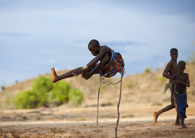 [Mucubal kid jumping – Angola. In Mucubal tribe, when you live in the bush, no PSP, no WII, no TV, no Radio..so the game the kids like the most is to jump over a wood hurdle. They have to touch a stone in front of the hurdle before jumping.
Mucubal (also called Mucubai, Mucabale, Mugubale) people are a subgroup of the Herero ethnic group, which means they are bantu speaking, and are supposed to have come from Kenya and to be related with Massais.
They are semi nomadic pastoralists living of cattle raising and agriculture. They live in a large area between the slopes of Chela Mounts in the north, and River Cunene to the south, where they are believed to have stopped during the Herero migration, about 300 years ago.
Mucubal have some very specific customs and traditions. They only are interested in cattle and do not care of the rest of the world outside of the bush. Mucubals are not allowed to mention people’s name in public, except their parent’s one, and children’s name in general. A married couple is not allowed to talk to each other in public, as long as the wife hasn’t had children. They only can speak to each other in private. Girls have their upper teeth sharpened and lower ones removed. In order to convince young girls to have their lower teeth removed, old men make them believe, that their teeth leave their mouth during the night, to go in a hole dug to relieve themselves and return in their mouth covered with excrement. The family structure and organization is also very specific. The father has the authority and is the head of the family, although the matrilineal descent is considered more important, as they inherit throught the mother's family. For example the son of the Soba -chieftain of the village-’s sister is the heir of the Soba. It is possible to be disowned by their father's family but not by their mother's because for them this link is sacred. The maternal uncle has to provide his nephew with an ox, called Remussungo. However a father provides his son with an ox, called Hupa. Mucubal can only get married with an outsider of the clan, although it cannot be with a member of another tribe like a Himba for example. Marriages of convenience are the rule most of the time. The fiancée is presented to her future husband during the Fico ceremony, when she is fourteen or less. This ceremony consists in a party with the two families during which presents are offered. The couple has to wait a few more years before consummating the marriage in the centre of the village. Mucubal men can have several wives and are also allowed to sell their wife, if they don’t get along with her or even if they want to earn money, as a woman can be worth 2 cows, which is about 2000 euros and represents a lot of money. For a first marriage a woman can even be worth 3 or 4 cows.
Their nomadic lifestyle based on cycles, between nomadism and stays in the same places (where they settle their villages), accounts for their religious customs and the funerary rites they follow. Mucubal people believe in a God called Huku, Klaunga, Ndyambi. They also worship their ancestors' spirits called Oyo Handi and Ovi huku, which are considered inferior to their supreme divinity. Divination is very important in their culture. They use talismans and amulets to protect their herds or prevent adultery. Nevertheless Mucubal are not afraid of death. Funerals can last several days or weeks. They decorate their graves with cattle horns. The number of cows sacrificed are in relation with the importance of the deceased. This shows the importance of cattle in their culture. Cattle is only killed on special occasions, as Mucubal usually don’t eat meat but rather corn (when they manage to grow some), eggs, milk and chicken.
They don’t eat any fish because according to the legend, one of their chieftains was brought to the sea by the portuguese and never came back. So they think that fish kills men]. (Eric Lafforgue)
