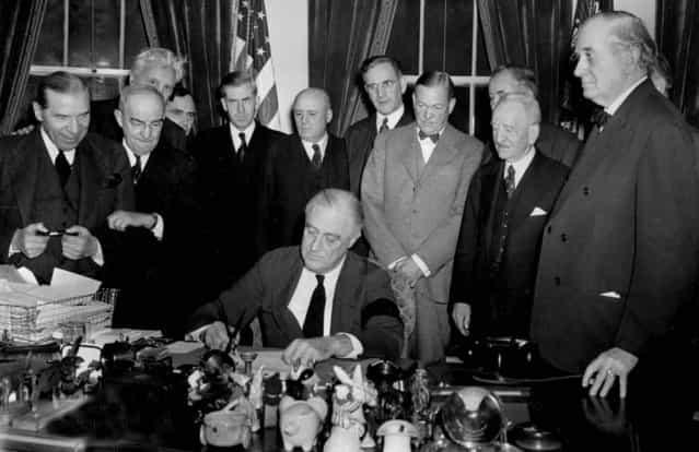 U.S. President Franklin D. Roosevelt signs the declaration of war at the White House in Washington, D.C., December 8, 1941 at 3:08 p.m. EST. Watching from left to right are, Rep. Sol Bloom, D-N.Y.; Rep. Luther Johnson, D-Texas; Rep. Charles A. Eaton, R-N.J.; Rep. Joseph Martin, R-Mass.; Vice President Henry A. Wallace; House Speaker Sam Rayburn, D-Texas; Rep. John McCormack, D-Mass.; Sen. Charles L. McNary, R-Ore.; Sen. Alben W. Barkley, D-Ky.; Sen. Carter Glass, D-Va.; and Sen. Tom Connally, D-Texas. (Photo by Associated Press)