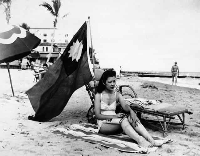 Ruth Lee, hostess at a Miami Chinese restaurant, is seen December 15, 1941. She didn't want to be mistaken for Japanese when she sunbathed on her days off, so she brought along a Chinese flag. Miss Lee was actually American-born. (Photo by Associated Press)