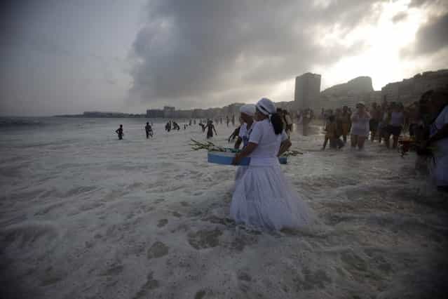 Followers of Afro-Brazilian religion Umbanda carry flowers and offerings for Iemanja, goddess of the sea, in Copacabana Beach in Rio de Janeiro December 29, 2012. Every end of the year, worshippers present gifts to the sea goddess to give thanks for the year that is finishing and ask for blessings for the upcoming new year. (Photo by Ricardo Moraes/Reuters)