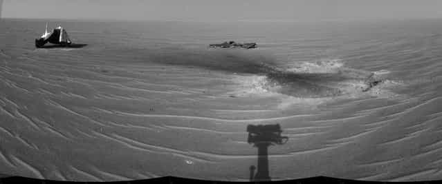 Opportunity gained this view of its own heat shield during the rover's 325th martian day (December 22, 2004). The main structure from the successfully used shield is to the far left. Additional fragments of the heat shield lie in the upper center of the image. The heat shield's impact mark is visible just above and to the right of the foreground shadow of Opportunity's camera mast. (Photo by NASA/JPL/The Atlantic)