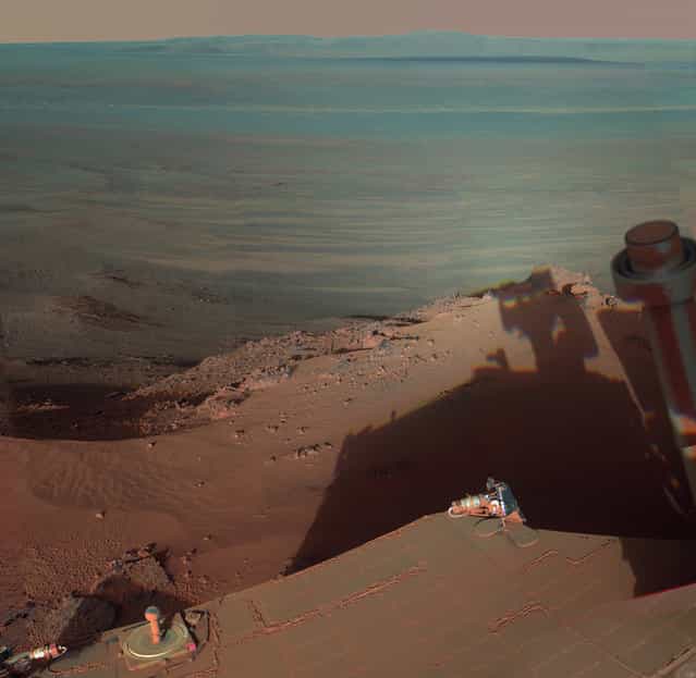Opportunity catches its own late-afternoon shadow in a view eastward across Endeavour Crater on Mars. The rover used a panoramic camera between about 4:30 and 5:00 p.m. local Mars time to record images taken through different filters and combined into this mosaic view. The view is presented in false color to make some differences between materials easier to see, such as the dark sandy ripples and dunes on the crater's distant floor. (Photo by AP Photo/NASA/JPL-Caltech/Cornell/ASU/The Atlantic)