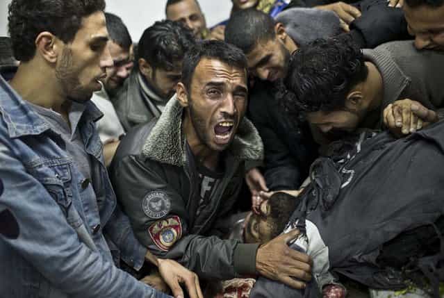 In this November 18, 2012 photo, a man cries next the body of a dead relative in the morgue of Shifa Hospital in Gaza City. This photo was one in a series of images by Associated Press photographer Bernat Armangue that won the first place prize in the World Press Photo 2013 photo contest for the Spot News series category. (Photo by Bernat Armangue/Associated Press)