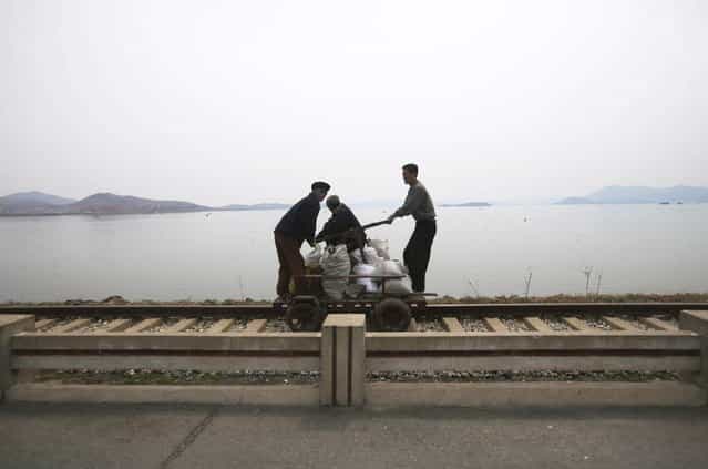 In this April 21, 2011 photo, men operate a manual rail car on tracks running along the West Sea barrage near Nampho, North Korea. (Photo by David Guttenfelder/AP Photo)