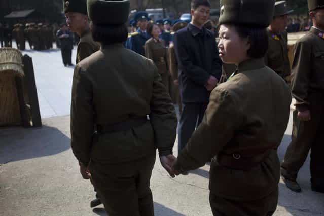 In this April 13, 2011 photo, two female North Korean soldiers hold hands as they tour the birthplace of Kim Il Sung at Mangyongdae, North Korea. (Photo by David Guttenfelder/AP Photo)