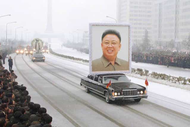 In this photo taken on December 28, 2011 a car carries a portrait of Kim Jong-Il during the funeral procession in Pyongyang. Millions of grief-stricken people turned out to mourn Kim Jong-Il, whose death has left the world scrambling for details about his young successor. (Photo by Reuters/Kyodo)
