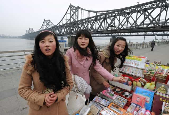 Chinese tourists buy North Korean souvenirs beside the Yalu River Bridge leading to North Korea during the funeral of the late leader Kim Jong Il, at the Chinese border town of Dandong on December 28, 2011. (Photo by Mark Ralston/AFP Photo)