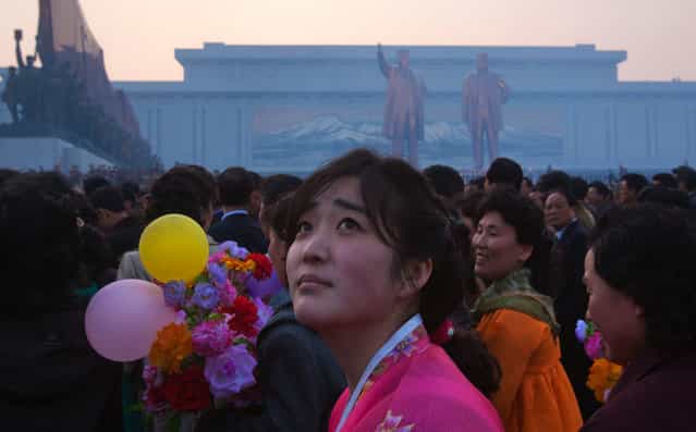 A North Korean woman looks up at balloons overhead at the end of an unveiling ceremony for statues of the late leaders Kim Il Sung and Kim Jong Il in Pyongyang, on April 13, 2012. (Photo by David Guttenfelder/AP Photo)