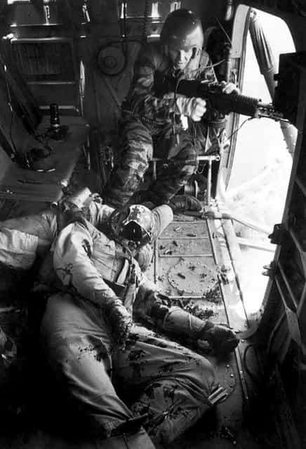 [Farley, unable to leave his gun position until YP13 is out of enemy range, stares in shock at YP3's co-pilot, Lieutenant Magel, on the floor]. (Photo by Larry Burrows/Time & Life Pictures)