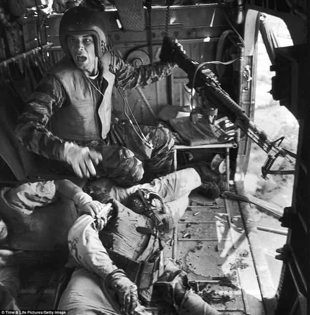 [Somebody help: James C. Farley (left) with a jammed machine gun shouts to crew as wounded pilot James E. Magel lies dying beside him]. (Photo by Larry Burrows/Time & Life Pictures)