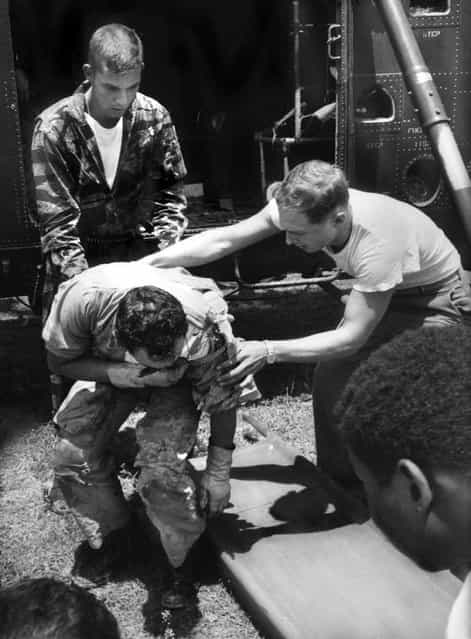 Back at Da Nang, wounded Sergeant Owens is eased out of the copter by Farley and a fellow Marine. (Photo by Larry Burrows/Time & Life Pictures)