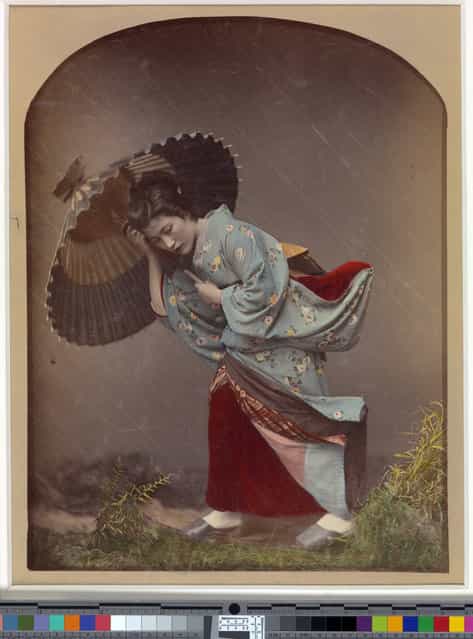 [Woman with Umbrella in Rain] by Raimund von Stillfried. Artist: Kusakabe Kimbei (Japanese, 1841–1934), 1870s. Commercial photography studios in Meiji-era Japan were renowned for the subtlety and refinement of their coloring techniques. This hand-tinted image of a young woman caught in a heavy rainstorm achieved its naturalistic effect by knitting together multiple strands of artifice: the greenery in the foreground was a studio prop; the flaps of the kimono were suspended by thin wires to create the impression of a strong wind; and long, diagonal marks were made on the negative to suggest streaks of rain. (Photo courtesy of The Metropolitan Museum of Art)