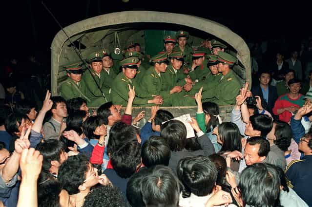 Pro-democracy demonstrators raise their fists and flash the victory sign in Beijing while stopping a military truck filled with soldiers on its way to Tiananmen Square on the day when then Prime Minister Li Peng declared Martial Law, May 20, 1989. (Photo by Catherine Henriette/AFP Photo)