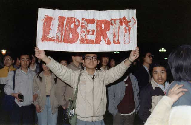 A student displays a banner with one of the slogans chanted by the crowd of some 200,000 pouring into Tiananmen Square, on April 22, 1989 in Beijing. They were attempting to participate in the funeral ceremony of former Chinese Communist Party leader and liberal reformer Hu Yaobang, during an unauthorized demonstration to mourn his death. His death in April triggered an unprecedented wave of pro-democracy demonstrations. (Photo by Catherine Henriette/AFP Photo)