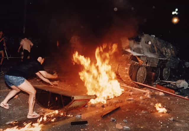 A student protester puts barricades in the path of an already burning armored personnel carrier that rammed through student lines during an army attack on anti-government demonstrators in Beijing's Tiananmen Square, early June 4, 1989. A govenment soldier who escaped the armored vehicle was killed by demonstrators. Pro-democracy protesters occupied the square for seven weeks; hundreds died in the early hours of June 4, 1989 when troops shot their way through Beijing's streets to retake the square. (Photo by Jeff Widener/AP Photo)