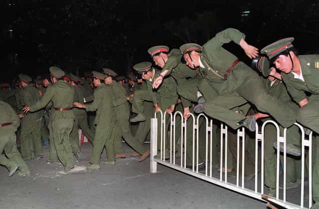 People's Liberation Army (PLA) soldiers leap over a barrier on Tiananmen Square on June 4, 1989, during heavy clashes with people and dissident students. The PLA was reportedly under orders to clear the square by 6:00 am, with no exceptions. (Photo by Catherine Henriette/AFP Photo)
