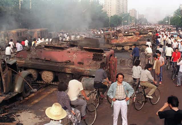 Beijing residents inspect the interior of more than 20 armored personnel carriers burned by demonstrators to prevent the troops from moving into Tiananmen Square, on June 4, 1989. (Photo by Manuel Ceneta/AFP Photo)