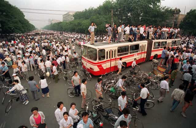 A huge crowd gathers at a Beijing intersection where residents used a bus as a roadblock to keep troops from advancing toward Tiananmen Square in this June 3, 1989 photo. (Photo by Jeff Widener/AP Photo)