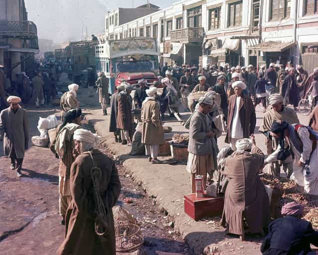 Men stroll past roadside vendors as a painted truck makes its way through the busy street in Kabul, Afghanistan, November, 1961. (Photo by Henry S. Bradsher/AP Photo via The Atlantic)