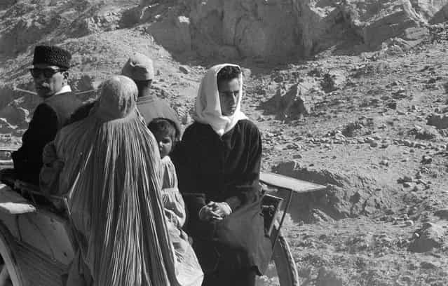 Afghan women, men, and child in traditional dress ride in a cart through an arid, rocky landscape, November, 1959. (Photo by Robert P. Martin/LOC via The Atlantic)