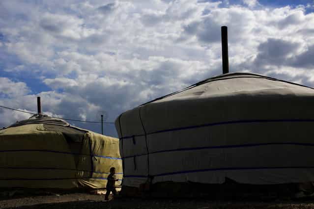 A boy stands next to a ger, a traditional Mongolian tent, in an area known as a ger district in Ulan Bator June 22, 2013. Approximately 60 percent of the population of Ulan Bator live in settlements known as ger districts and in many cases residents have limited access to basic services such as water and sanitation. According to a 2010 National Population Center census, every year between thirty and forty thousand people migrate from the countryside to the capital Ulan Bator. Ger districts in the city have been expanding rapidly in recent years. Mongolia is the world's least densely populated country, with 2.8 million people spread across an area around three times the size of France. (Photo by Carlos Barria/Reuters)