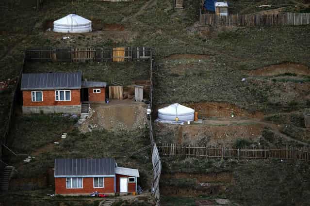 Gers, traditional Mongolian tents, stand next to houses in an area known as a ger district in Ulan Bator June 26, 2013. Approximately 60 percent of the population of Ulan Bator live in settlements known as ger districts and in many cases residents have limited access to basic services such as water and sanitation. According to a 2010 National Population Center census, every year between thirty and forty thousand people migrate from the countryside to the capital Ulan Bator. Ger districts in the city have been expanding rapidly in recent years. Mongolia is the world's least densely populated country, with 2.8 million people spread across an area around three times the size of France. (Photo by Carlos Barria/Reuters)