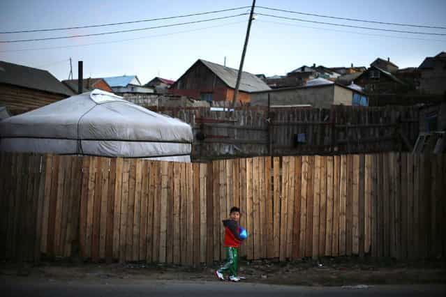 A boy walks along a street next to a ger, a traditional Mongolian tent, in an area known as a ger district in Ulan Bator June 26, 2013. Approximately 60 percent of the population of Ulan Bator live in settlements known as ger districts and in many cases residents have limited access to basic services such as water and sanitation. According to a 2010 National Population Center census, every year between thirty and forty thousand people migrate from the countryside to the capital Ulan Bator. Ger districts in the city have been expanding rapidly in recent years. Mongolia is the world's least densely populated country, with 2.8 million people spread across an area around three times the size of France. (Photo by Carlos Barria/Reuters)