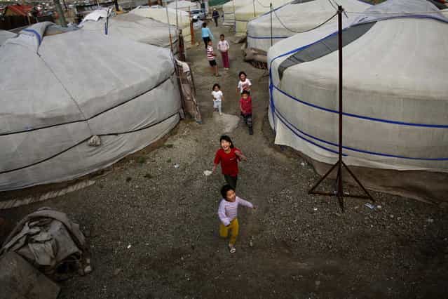 Children play near gers, traditional Mongolian tents, in an area known as a ger district in Ulan Bator June 22, 2013. Approximately 60 percent of the population of Ulan Bator live in settlements known as ger districts and in many cases residents have limited access to basic services such as water and sanitation. According to a 2010 National Population Center census, every year between thirty and forty thousand people migrate from the countryside to the capital Ulan Bator. Ger districts in the city have been expanding rapidly in recent years. Mongolia is the world's least densely populated country, with 2.8 million people spread across an area around three times the size of France. (Photo by Carlos Barria/Reuters)