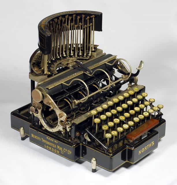 Norths. North's Typewriter Manufacturing Co. Ltd., London, 1892. The North’s typewriter has the rare design feature of having its type-bars stand up vertically behind the carriage. This gives visible typing, with the type bars swinging down to the top of the platen. However this configuration creates a complicated paper-handling situation that requires two [holding baskets] in the carriage, one for the paper to be rolled into before typing and the other for the paper to roll up into as one typed. So visible typing was achieved but only to the extent that a few lines could be seen before the paper advanced into the lower holding basket. The typewriter got its name from Lord North, who bought the factory where the English typewriter had been made in 1890 and financed the development of the North's typewriter which appeared in 1892. (Photo and caption by Martin Howard/Martin Howard Collection)