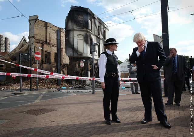 London Mayor Boris Johnson stands with Police Superintendent Jo Oakley near burnt out Reeves Corner furniture store on August 9, 2011 in Croydon, England