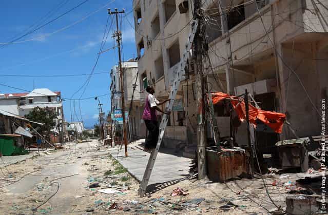 A Mogadishu municipal electrician climbs to inspect jumbled power connections in the Bakara market