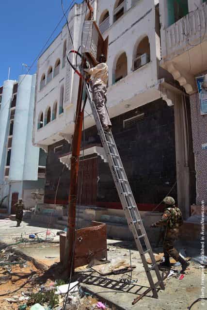 A Mogadishu municipal electrician climbs to inspect jumbled power connections in the Bakara market
