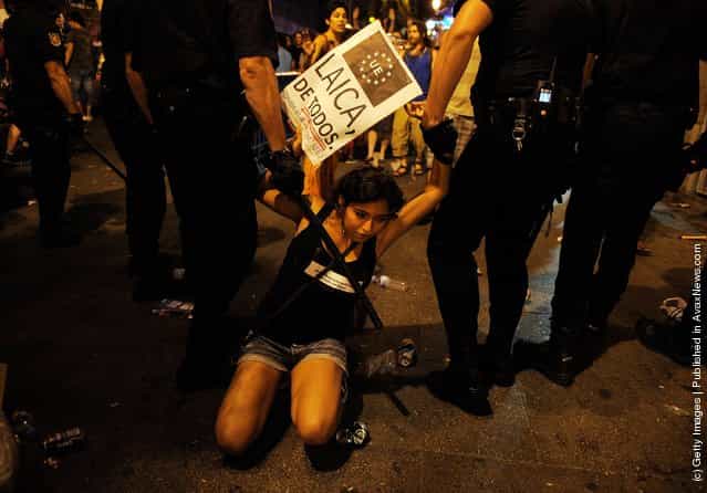 A girl is moved on by police after disturbances during a protest against the World Youth Day 2011 celebrations