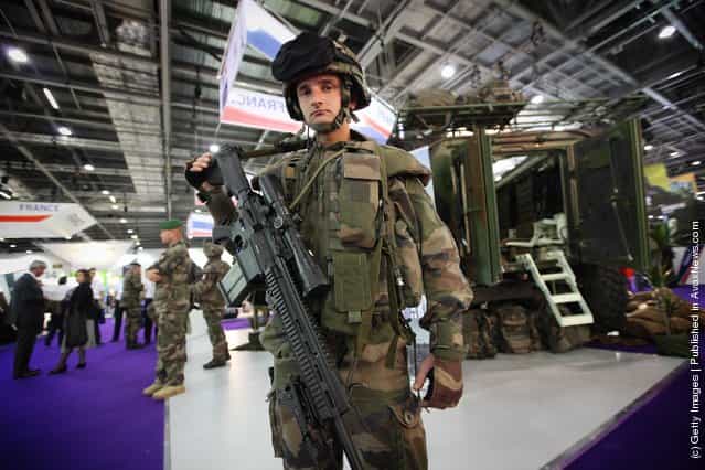 A French soldier stands near a military combat command vehicle on display at The Defence and Security Exhibition