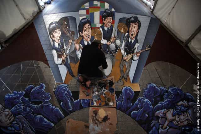 Street artist Juandres Vera puts the finishing touches to a giant 3d pavement mural of The Beatles