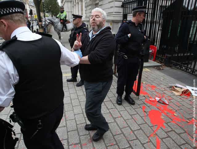An anti-war protestor is detained by a policeman at the gates of Downing Street
