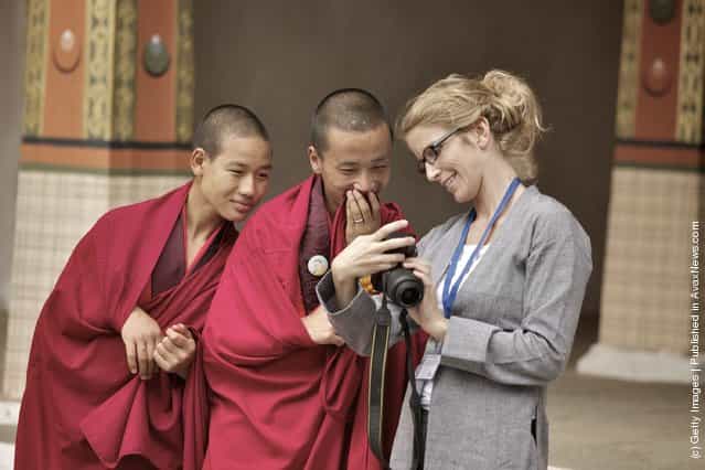 Young monks laugh at their own photos taken by a German photojournalist in the main courtyard of the Dzong