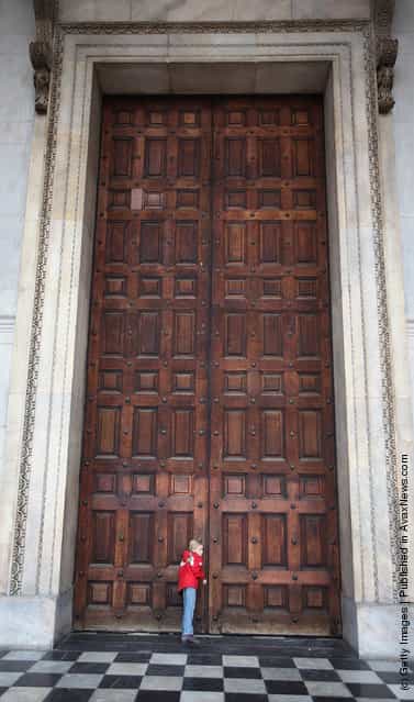 A girl listens at the closed west door of St Paul's Cathedral