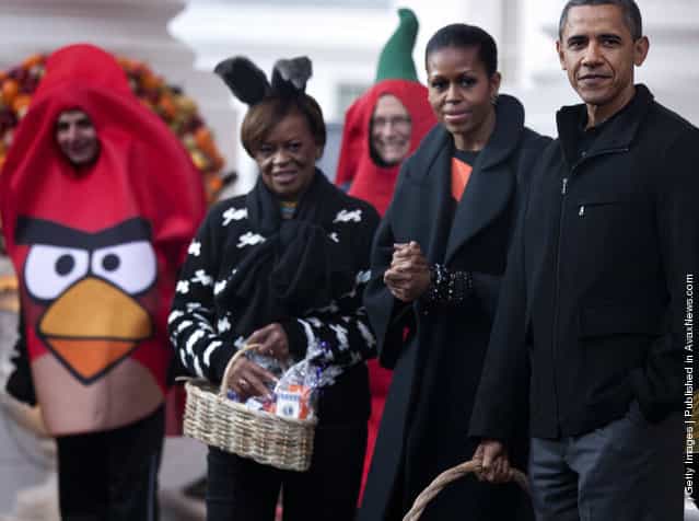 President Barack Obama waits with first lady Michelle Obama and her mother Marian Robinson to greet trick or treaters at the White House