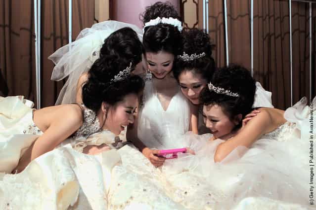 Models looks at an iphone backstage before Tsai Meiyue Wedding Dress S/S 2012 of China Fashion Week
