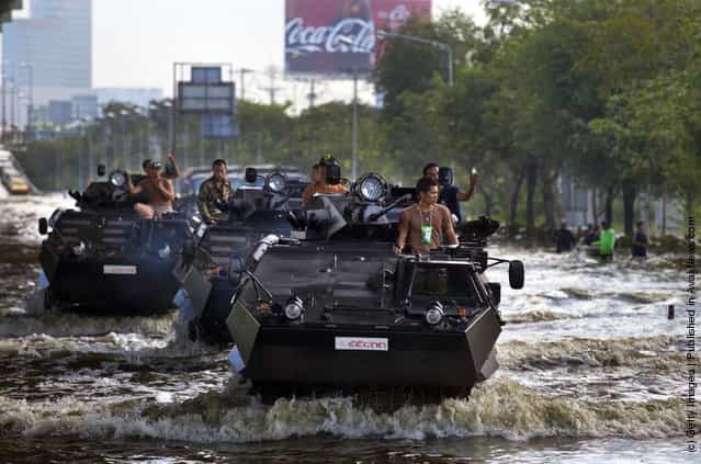 Thai military plow through the water into the flood zone in armored personnel carriers