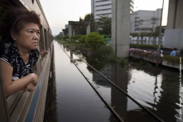 A Thai woman looks out at the water on a train as it makes its way on limited stops through the flooded region in the Laksi area