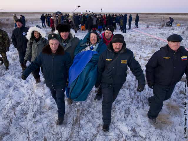Expedition 29 Commander Mike Fossum smiles as he is carried in a chair to the medical tent just minutes after he and Expedition 29 Flight Engineers Sergei Volkov and Satoshi Furukawa landed