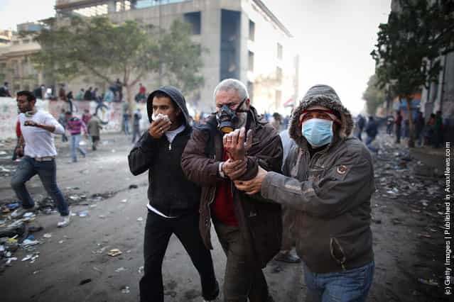 An injured protestor is led away during clashes with police near Tahrir Square