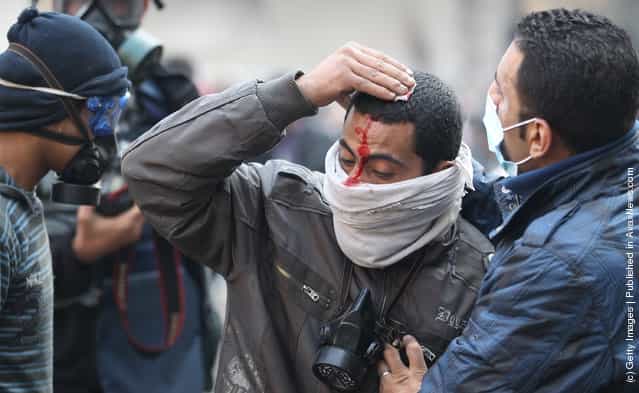 An injured protestor is led away during clashes with police near Tahrir Square