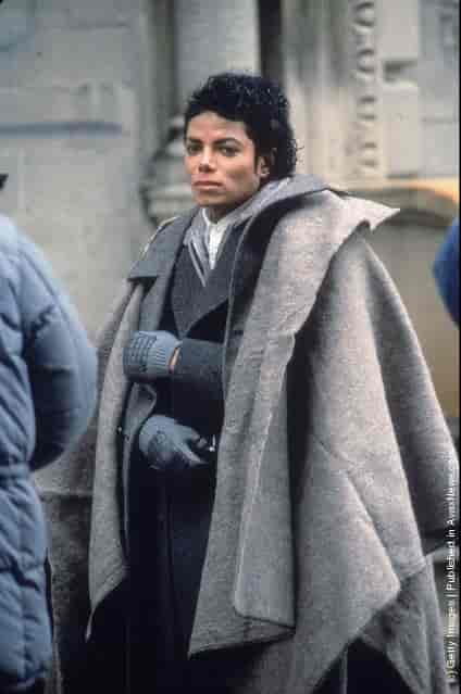 Popular American musician Michael Jackson (1958 - 2009) stands with a blanket over his shoulders during a break in the filming of the long-form music video for his song Bad, directed by Martin Scorsese, New York, New York, November 1986