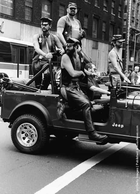 A group of men dressed in leather fetish clothing ride in a truck at the intersection of 32nd Street and Fifth Avenue during the annual Gay Pride parade in New York City, c. 1980